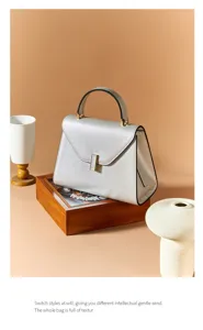 Silver leather handbag for women, elegant commuter shoulder bag with top handle and metal lock.