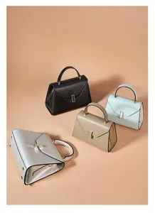 Four elegant leather handbags in four colors with metal clasps on studio backdrop.