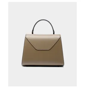 Elegant trapezoid leather handbag detail, featuring top handle and sleek envelope flap design.