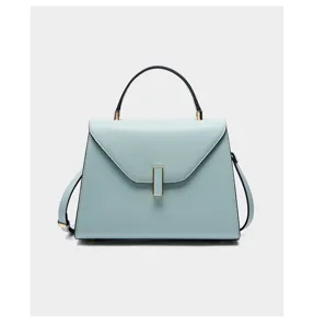 Detailed view of light blue leather handbag, featuring exquisite metallic clasp and sturdy handle.