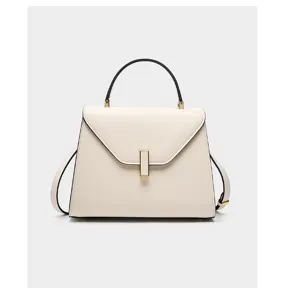 White leather handbag detail, classic trapezoid structure with sleek metal vertical clasp lock.