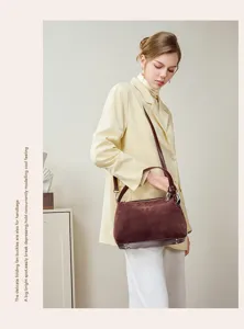 Detail view of brown suede shoulder bag featuring elegant folding metal buckles and zipper.