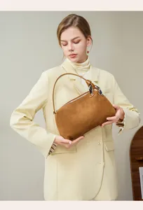 Detail view of the elegant brown suede shoulder bag featuring chic metal rings and zip closure.