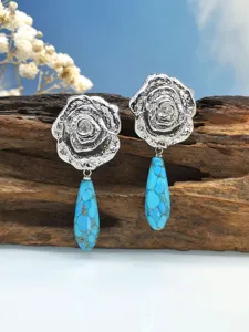 Primo piano dettagliato di orecchini rosa argento retro con ciondolo turchese blu.