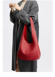 Close-up detail of red leather hobo shoulder bag worn by model, showing texture and design.