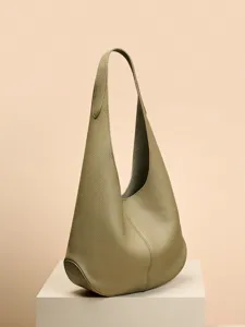 Minimalist leather hobo shoulder bag in a slouchy daily design, shown standing on a display pedestal.