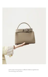 Detailed view of taupe leather handbag featuring top handle and stylish metal pyramid clasp.