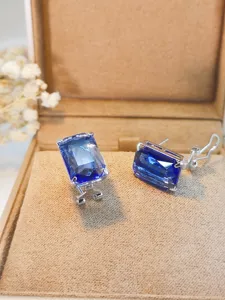 Primo piano di eleganti orecchini in argento con pietre blu rettangolari, dettagli raffinati.