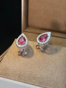 Dettaglio ravvicinato di lussuosi orecchini a goccia in zircone rosa con alone luminoso.