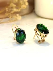 Primo piano dettagliato di orecchini pendenti con gemma verde ovale e montatura dorata.