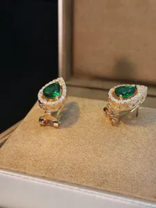 Dettaglio in primo piano di orecchini di cristallo verde a pera con zirconi cubici.