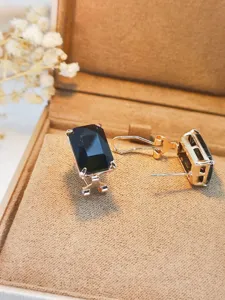 Primo piano dettagliato di orecchini con pietra nera rettangolare in una elegante scatola.
