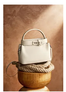 Close-up shot of the cream leather handbag highlighting the exquisite texture and metal details.