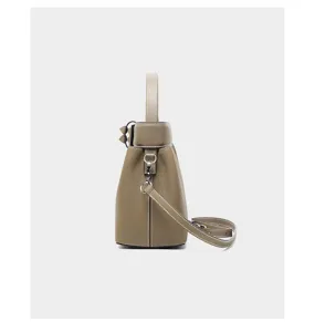 Leather bucket bag side detail showing fine stitching texture and metal ring hardware.