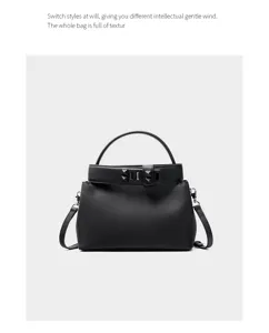 Detailed view of black leather top handle bag with metallic lock closure and pyramid studs.