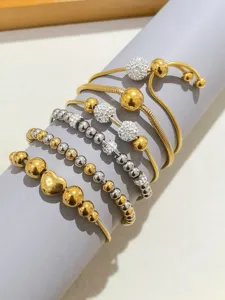 Primo piano di bracciali impilati color oro e argento con sfere di cristallo pavè.