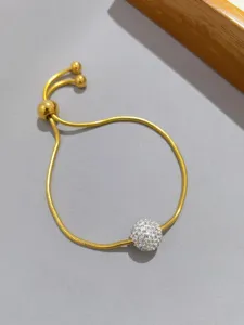 Dettaglio in primo piano del bracciale a catena serpente dorato con sfera e strass.