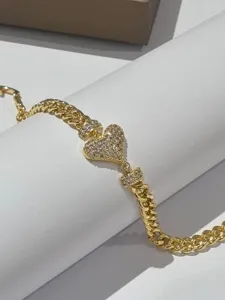 Dettaglio bracciale cuore in strass oro, elegante gioiello con catena gourmette di lusso per donna.