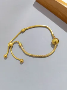 Dettaglio del bracciale a catena di serpente dorato con perle regolabili per stile chic.