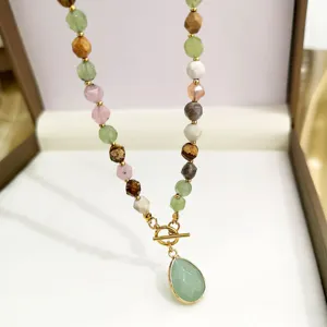 Primo piano dettaglio di una collana di perle in pietra naturale multicolore con ciondolo.