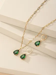 Dettaglio ravvicinato di una collana con ciondolo a goccia in zircone verde e orecchini abbinati.