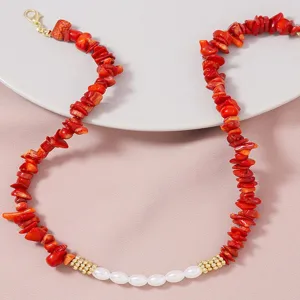 Collana artigianale di corallo rosso irregolare con perle bianche e dettagli dorati chic.