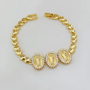 Nahaufnahme des vergoldeten Herzkettenarmbands mit drei diamantbesetzten Marien-Anhängern.