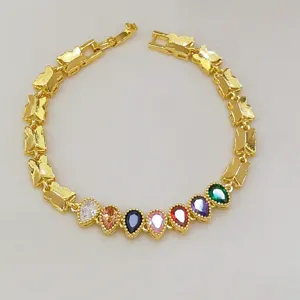 Dettaglio del bracciale dorato con maglie a farfalla e zirconi colorati in goccia.