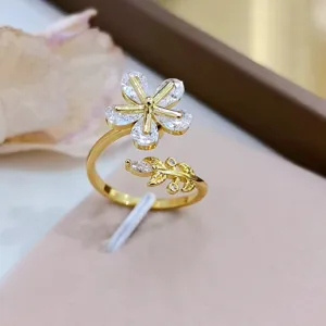 Squisito dettaglio di un anello aperto placcato in oro con fiore e foglia in zircone scintillante.