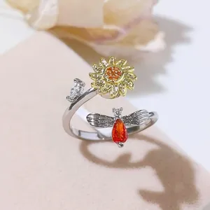 Primo piano dettagliato dell'anello aperto con girasole e ape, decorato con zirconi luminosi.