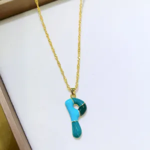 Primo piano dettagliato di una collana con ciondolo lettera smaltato colorato su vassoio.