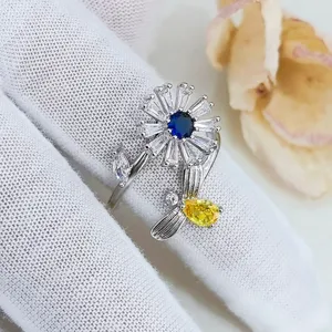 Primo piano dettagliato dell'anello fiore rotante con zirconi scintillanti, pietra blu e ape.
