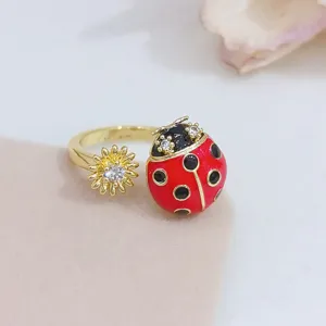 Vista dettagliata di anello aperto coccinella e girasole con zirconi cubici scintillanti in oro.
