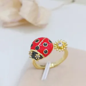 Primo piano dettagliato di un anello dorato con coccinella e fiore e zirconi cubici scintillanti.