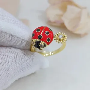 Anello aperto placcato in oro con graziosa coccinella in smalto rosso-nero e fiore in zircone brillante.