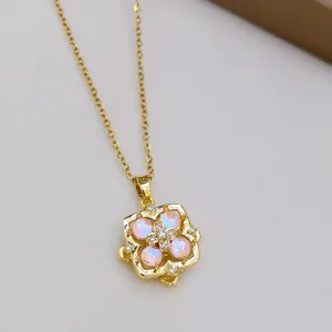 Dettaglio di collana dorata con delicato ciondolo floreale rosa e zirconi scintillanti.