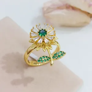 Anello a fiore rotante dorato con zirconi verdi e bianchi scintillanti, gioiello elegante.