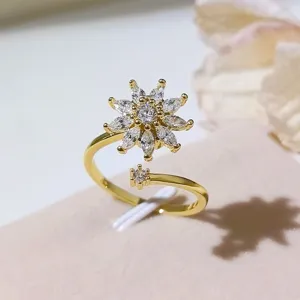 Primo piano dettagliato di un anello aperto dorato con motivo floreale in zircone cubico.