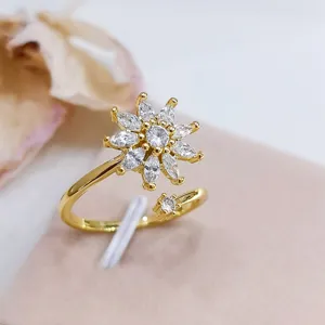 Dettaglio dell'anello aperto placcato in oro con design a fiore in zirconi brillanti.