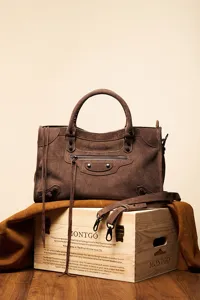 Detailed view of the brown suede motorcycle handbag with classic metal studs and tassel.