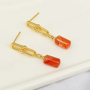 Primo piano dettagliato di orecchini pendenti dorati con pietre rosse dal design unico.