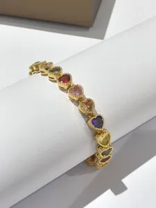 Bracciale con cuore in zirconi cubici colorati, dettaglio di gioielli moda dorati.