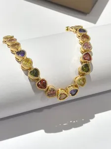 Vista dettagliata di un braccialetto con zirconi a cuore multicolore, dorato.