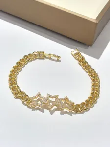 Dettaglio in primo piano di un bracciale a catena dorata con luminosi zirconi a stella.