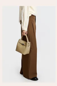 Detail view of khaki leather bucket bag featuring top handle and metal lock design.