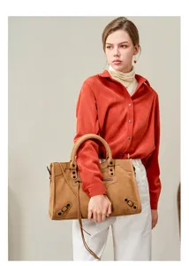 Detailed view of women brown suede motorcycle handbag with classic studs and shoulder strap.