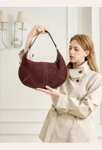 Primo piano della borsa hobo in camoscio marrone scuro, con cuciture a contrasto e texture in pelle.