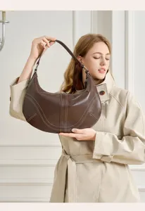 Vista di dettaglio della borsa a spalla hobo in pelle marrone con cuciture e anelli metallici.