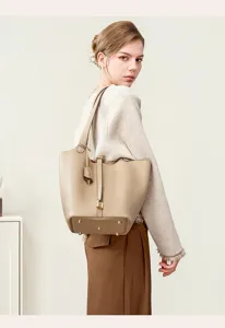 Detail view of the elegant beige leather bucket bag featuring a secure padlock and sturdy handles.