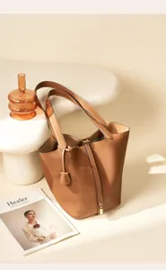 Genuine leather bucket bag for women, stylish brown shoulder tote with lock design for daily commuting.